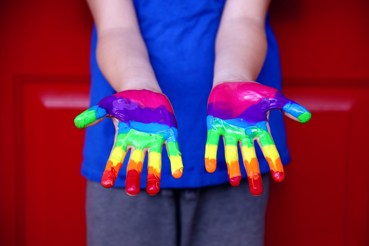 Kadr na dziecięce dłonie pomalowane na kolory tęczy