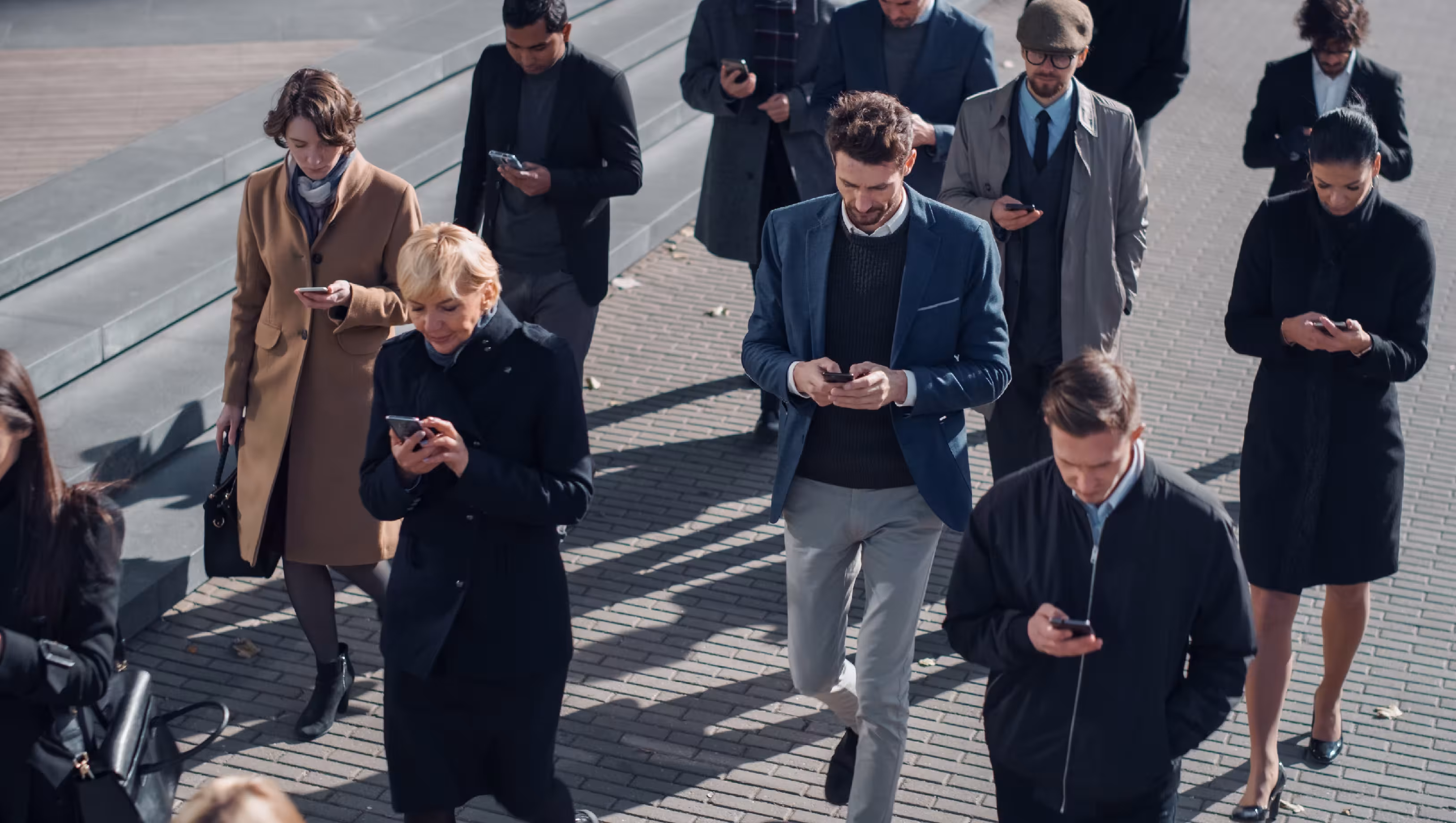 Tłum na ulicy, wszyscy wpatrzeni w telefony komórkowe