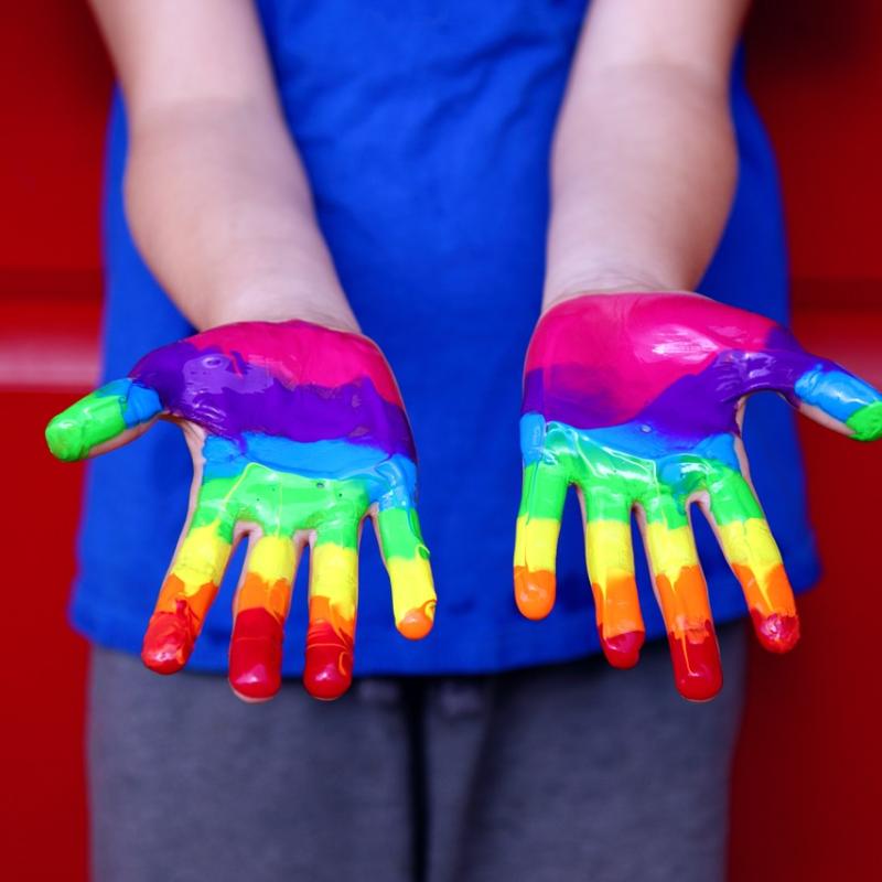 Kadr na dziecięce dłonie pomalowane na kolory tęczy