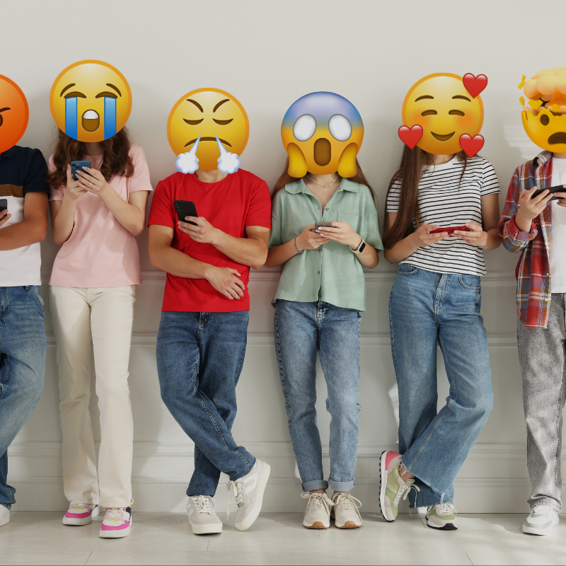 Zdjęcie przedstawiające sześcioro nastolatków wpatrzonych w telefony komórkowe, ich twarze zamienione na emotikony